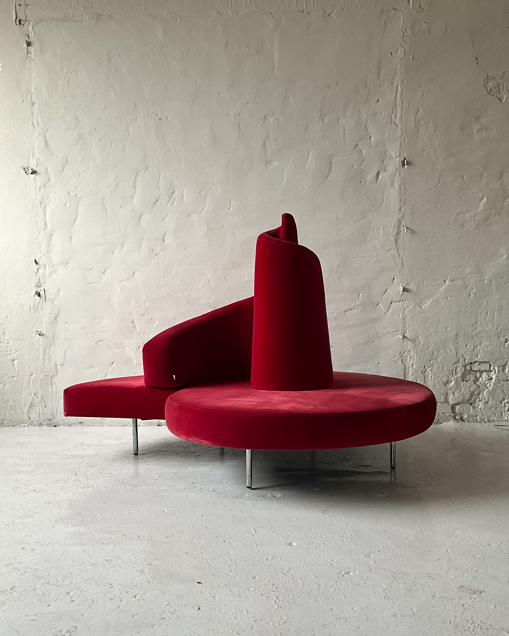 Czerwona sofa Edra Tatlin projektu Mario Cananzi i Roberto Semprini z 1989 roku, spiralne oparcie i welurowa tapicerka.