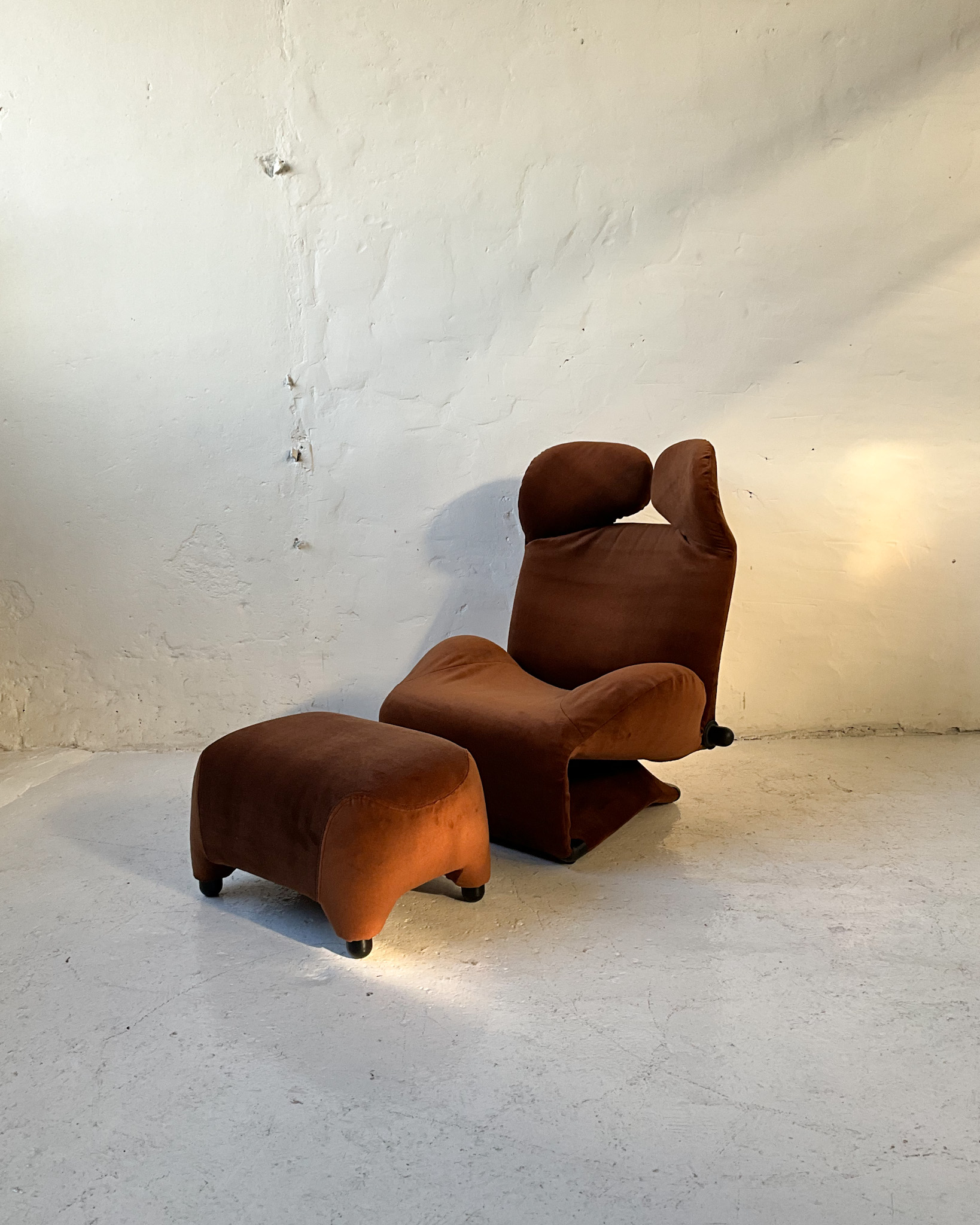 Fotel Cassina Wink z podnóżkiem projektu Toshiyuki Kita, brązowa welurowa tapicerka.